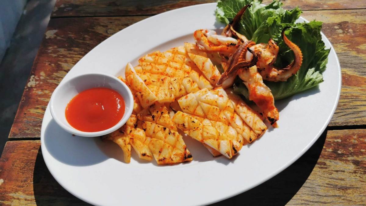 Mực một nắng vàng ươm đang được nướng trên bếp than hồng, toát lên hương thơm hấp dẫn, món hải sản nướng Phan Thiết
